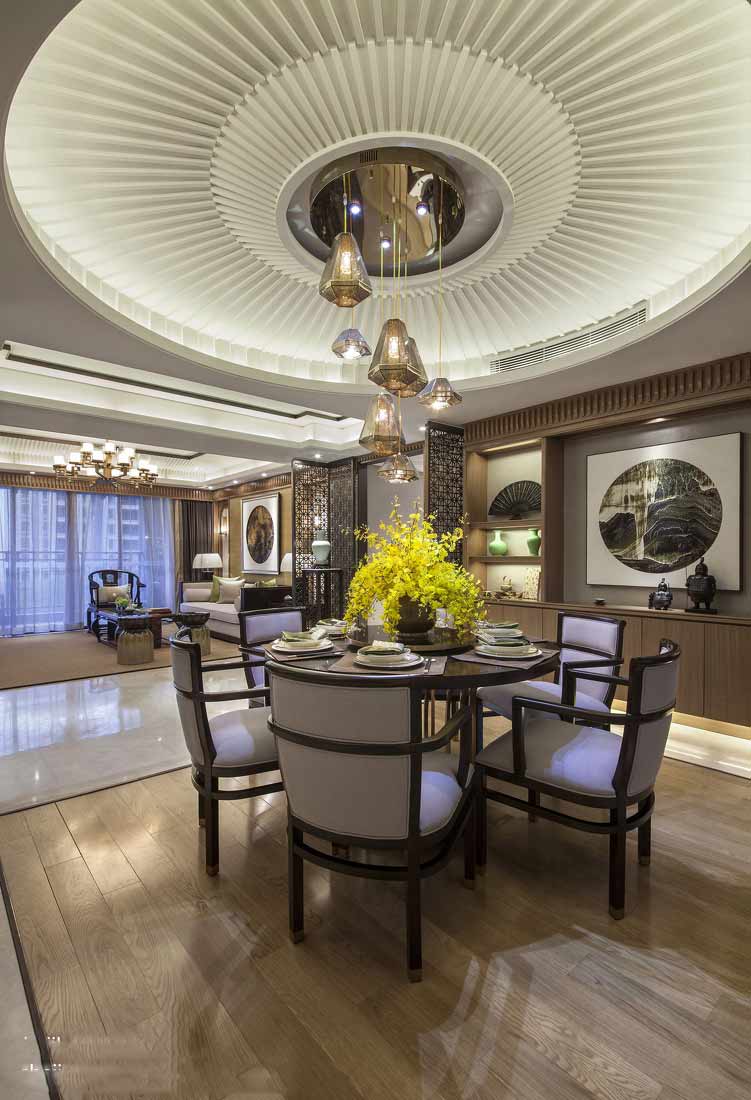 木质的地板和软性的椅子相得益彰，餐桌采用的是中式典型的圆桌，餐桌背景墙是中国的山水画和中式摆件。
