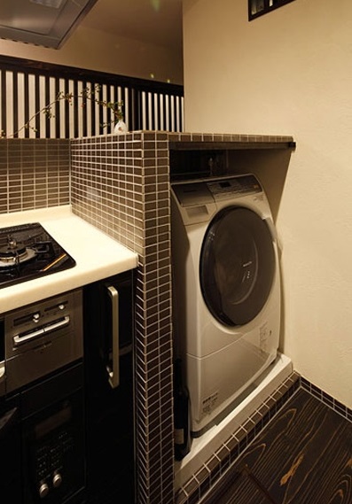 白色的厨台，搭配黑色的整体橱柜，黑白搭配，经典的色彩组合，令生活也显示出现代化的高贵气息。而深灰色马赛克的墙壁打造的收纳空间，正好摆放洗衣机，小角落也有大用处，增加了整体的收纳性。
