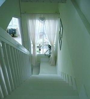 木质楼梯总能给人踏实的触感。从楼梯上方向下望，刚好能看到粉色的窗帘，清新而梦幻。