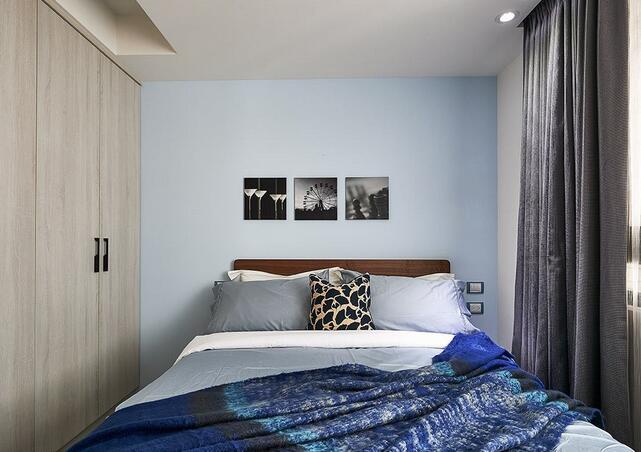 床头墙漆以淡雅的浅蓝色为主题，营造出了清爽明亮的休憩氛围。以黑白色的摄影作品制作为床头挂画，极具现代艺术特色。