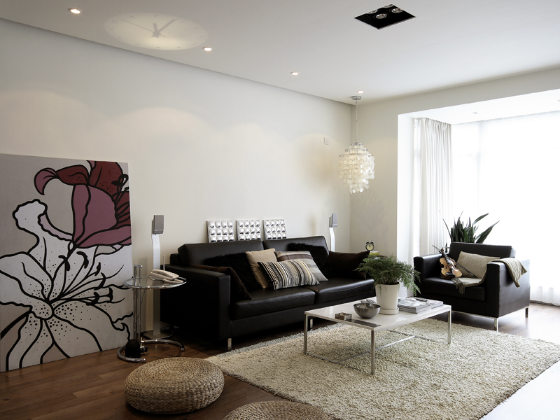 用大型画像代替了复杂的背景墙，沙发和地毯是简单的黑灰两色，设计师有意识地把客厅塑造成一个文艺的画室。