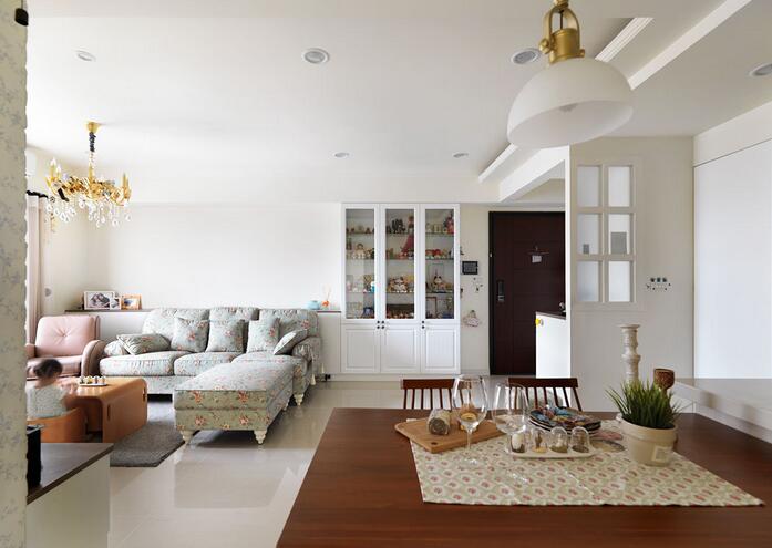 纯白色奠定了空间的清新气质。沙发背景墙面的柜体分割了入门区域与客厅的界线，线条干净利落。