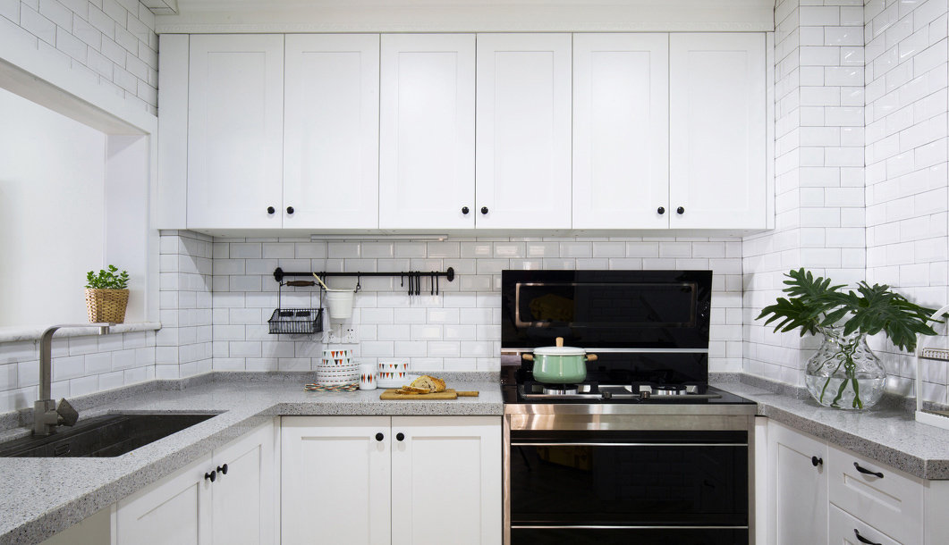 白色墙面砖和黑白大理石面板，让厨房的格调变得“精英”起来，角落处摆放几株绿植，让纯白的空间不至于太简单。