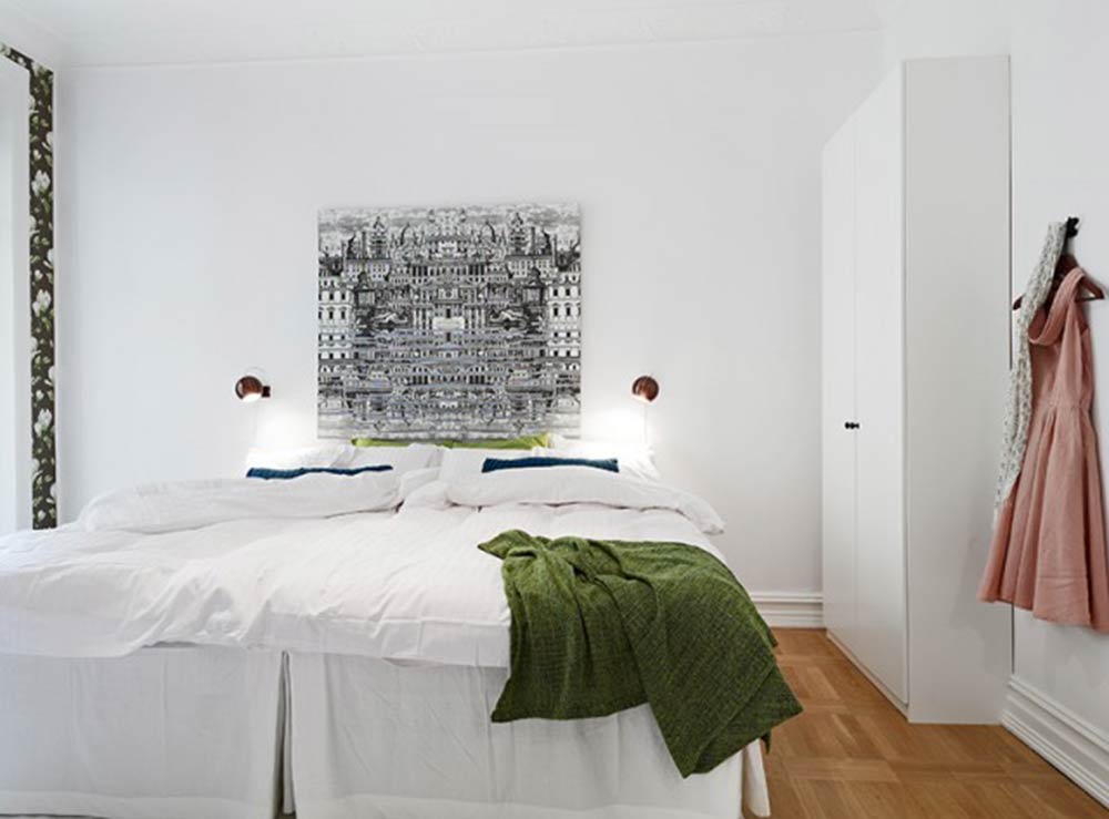 卧室中的白色大衣柜与墙壁融为一体，而正中间的黑色装饰画则格外显眼。