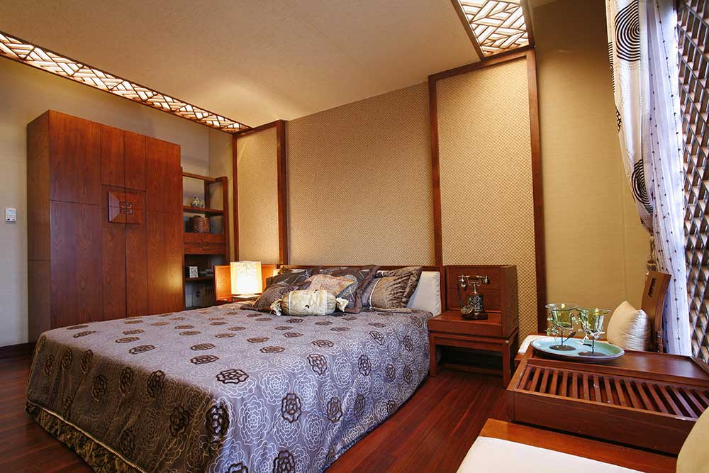 次卧墙壁均为米色壁纸装饰，红色木质床头柜、沙发、衣柜浑然一体，古色古香。