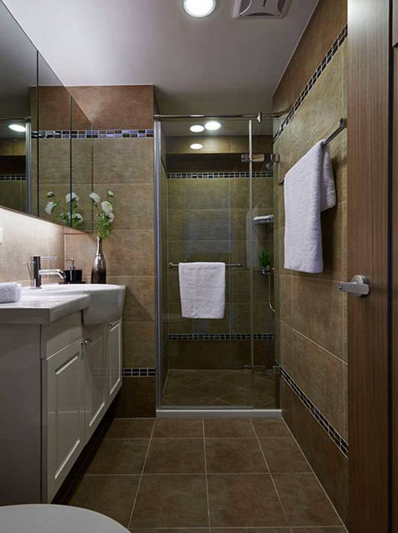与玄关同采板岩结合马赛克砖铺叙的客卫浴中，改采米黄砖色铺陈温暖氛围。